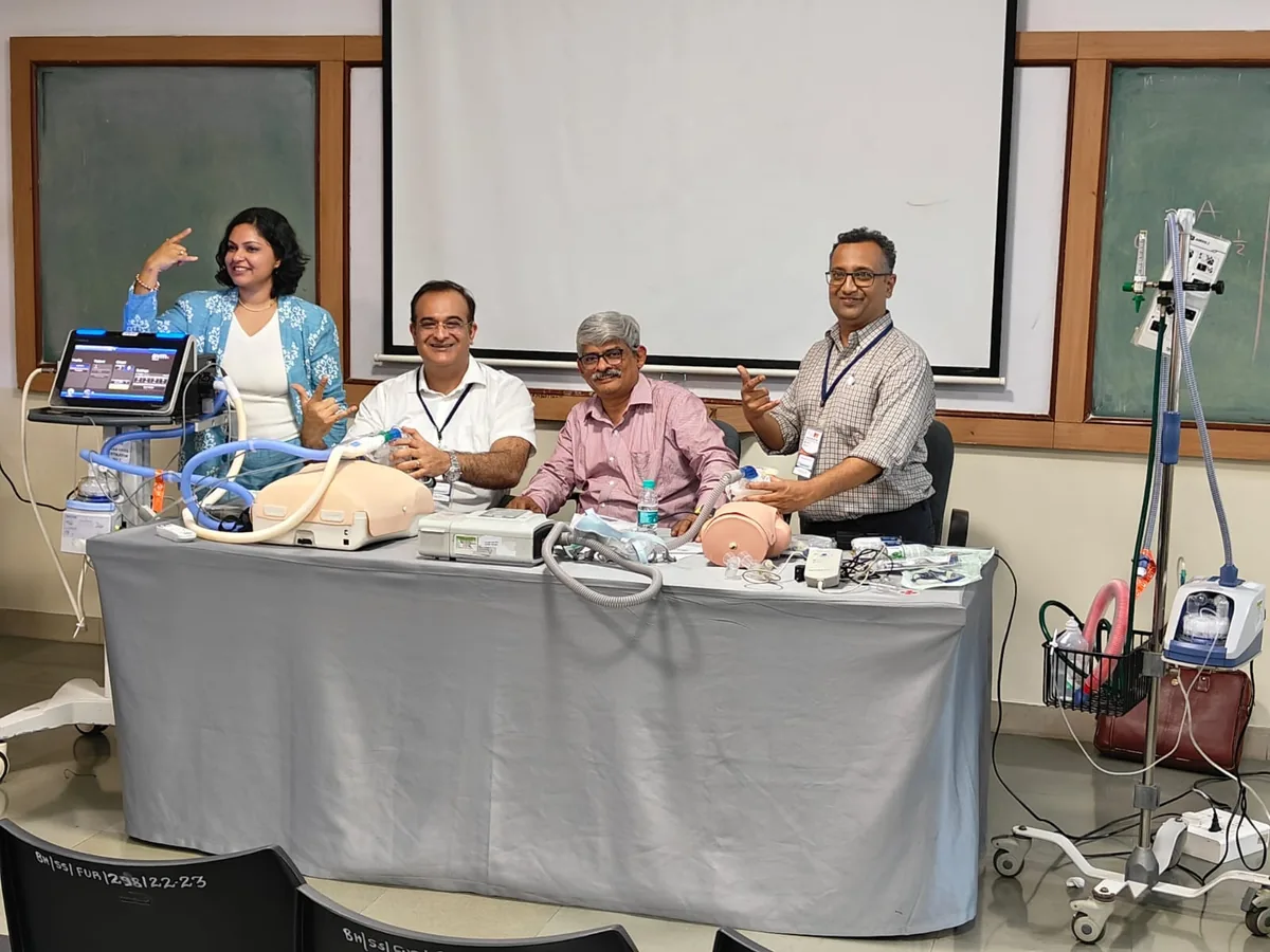Dr. Swathi Rao with faculty colleagues at a ventilation skills station set up with training mannequins, ventilators and breathing circuits
